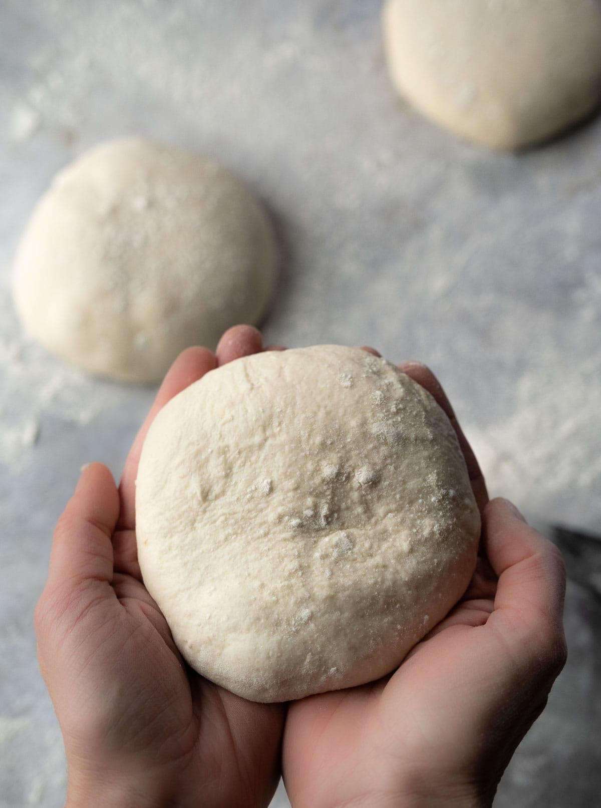 hands cupped to hold a sourdough pizza dough