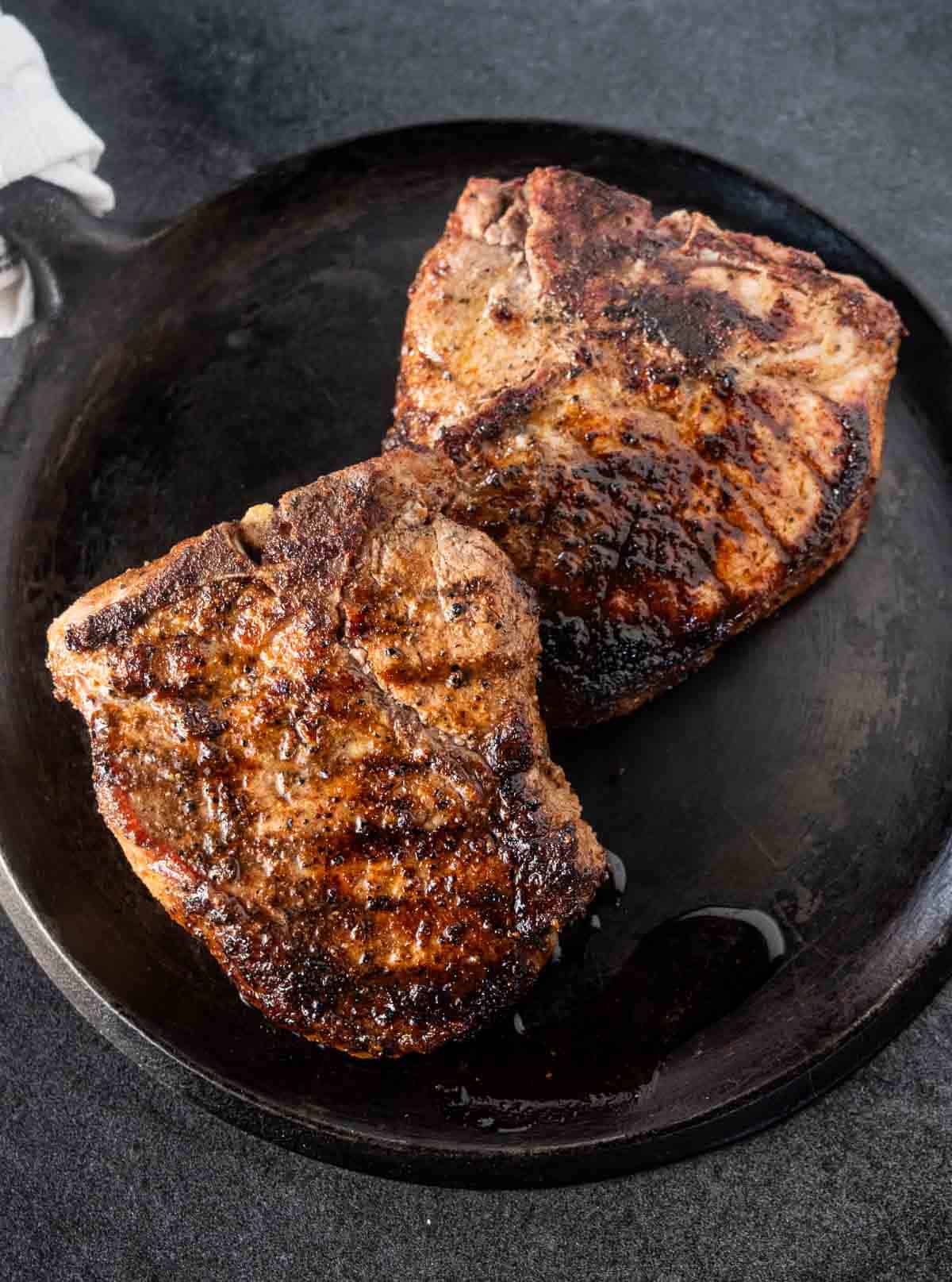 Pork steaks resting on a serving dish before slicing.