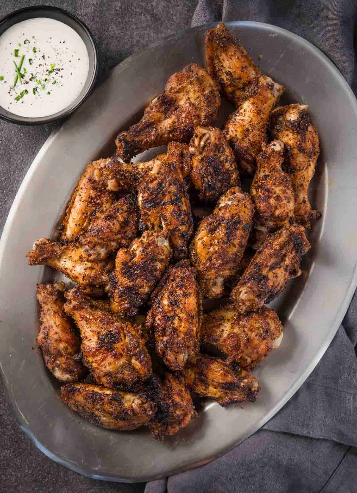 Dry Rub Chicken Wings on a silver platter next to a bowl of homemade ranch dressing