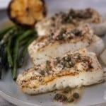 Grilled halibut on a platter topped with a butter caper lemon sauce