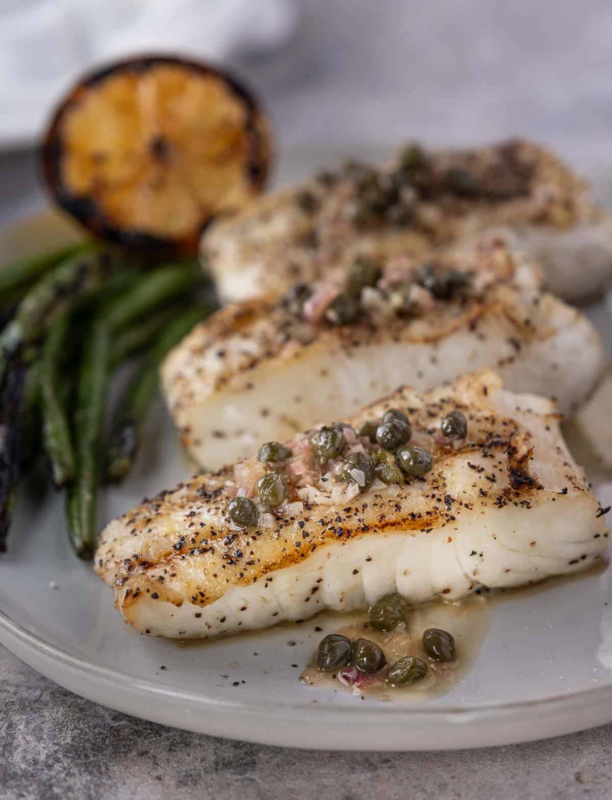 Grilled halibut on a platter topped with a wine butter caper lemon sauce