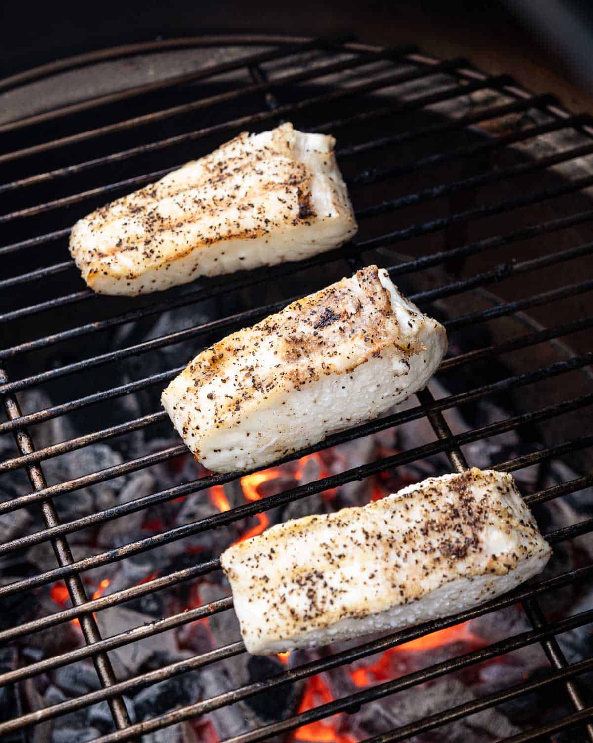 Halibut on the grill over direct heat after it has been flipped over once.