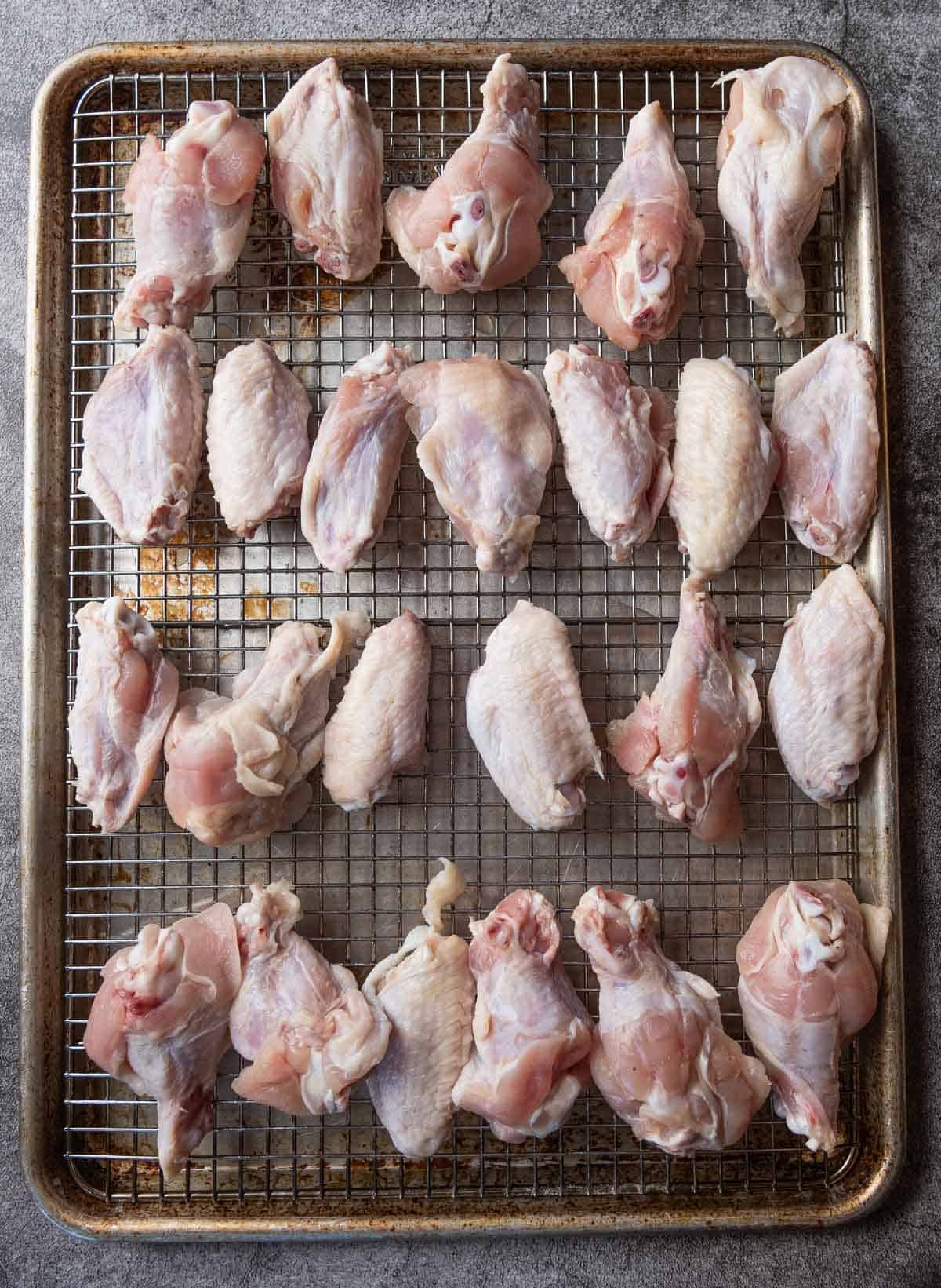 two dozen raw chicken wings on a baking sheet