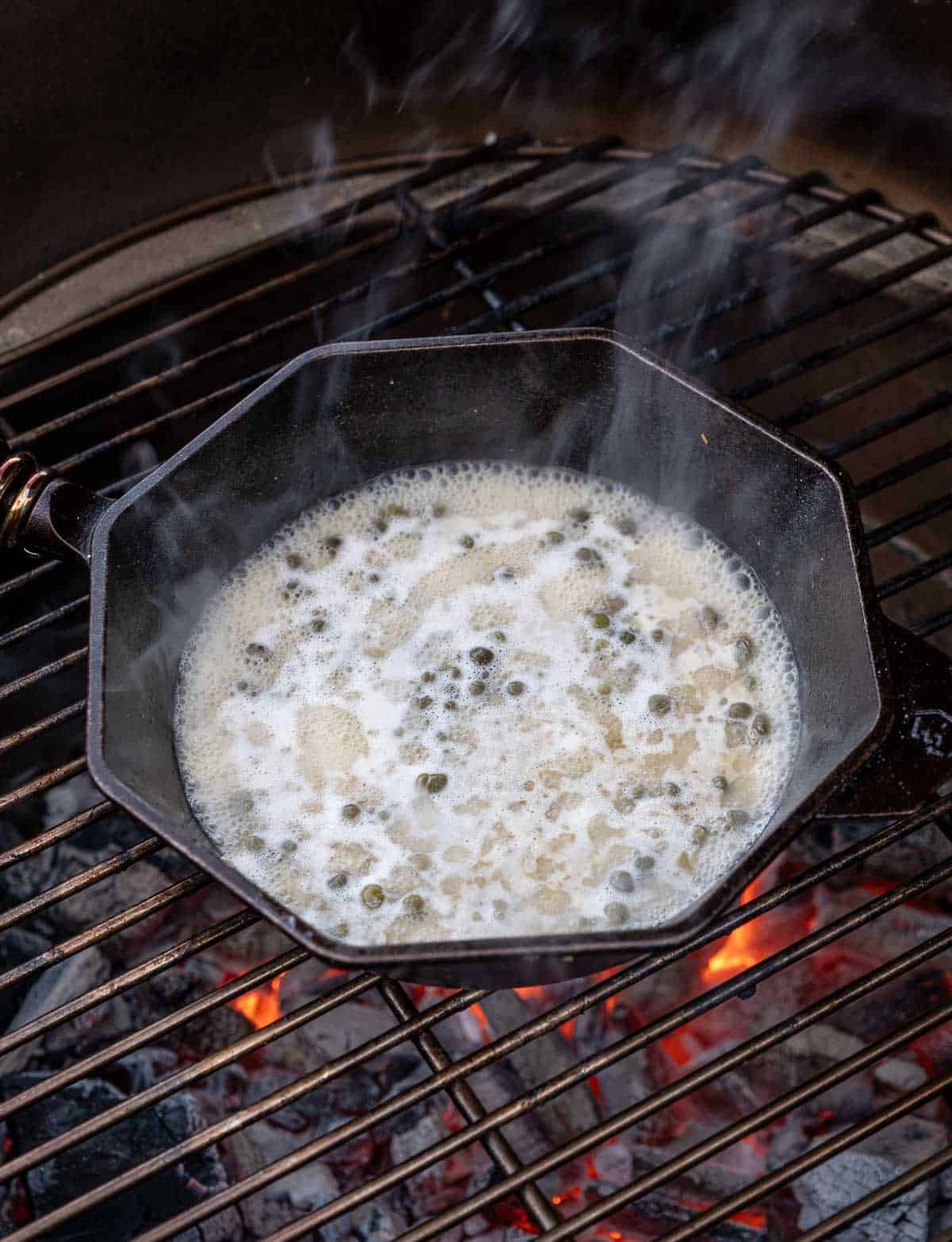 White wine butter sauce reduced in a cast iron pan over direct heat on the grill.