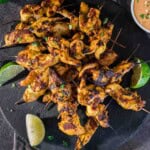 Grilled chicken satay skewers on a slate plate and peanut dipping sauce.