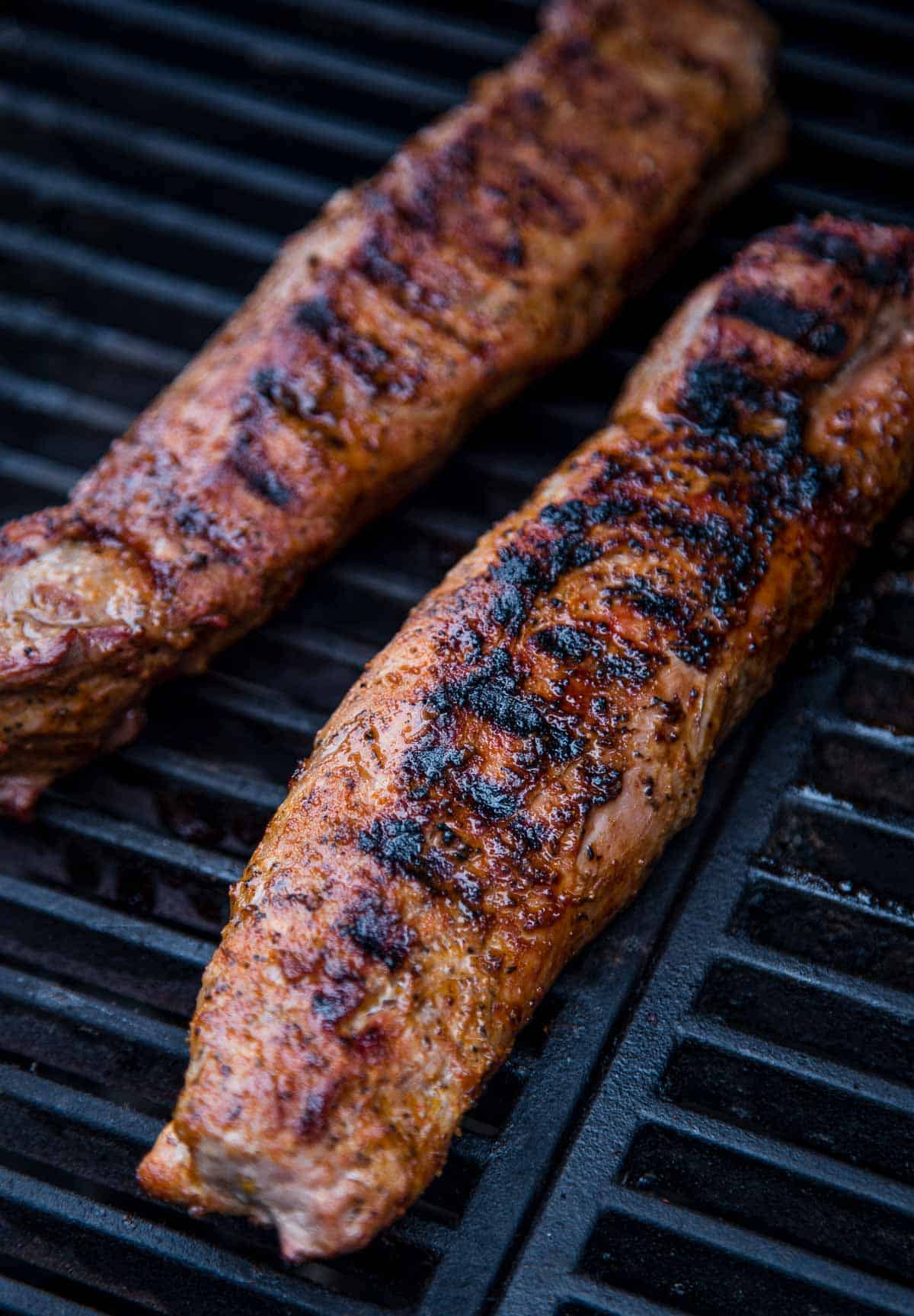 Two grilled pork tenderloins on a hot grill.