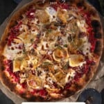 A top down image of a turkey pizza using leftover Thanksgiving turkey ingredients on a pizza peel.