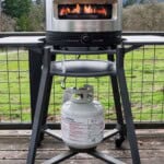 Solo Stove Pi Prime with the flame on high on top of a stand on a deck.
