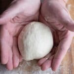 A Hand holding a pizza dough before it is frozen.