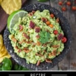 Smoked guacamole in a molcajete topped with bacon and cilantro surrounded by chips and greens.