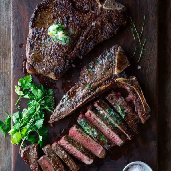 Two t-bone steaks on a cutting board, one sliced on a cutting board.