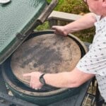 A pin showing sean from vindulge placing a pizza stone into a big green egg on the grill grates.