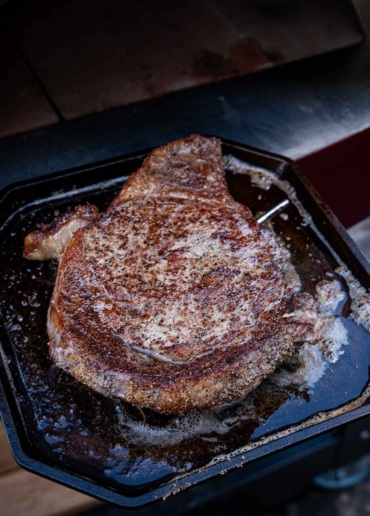 A steak on a cast iron griddle pan after being removed from the pizza oven.