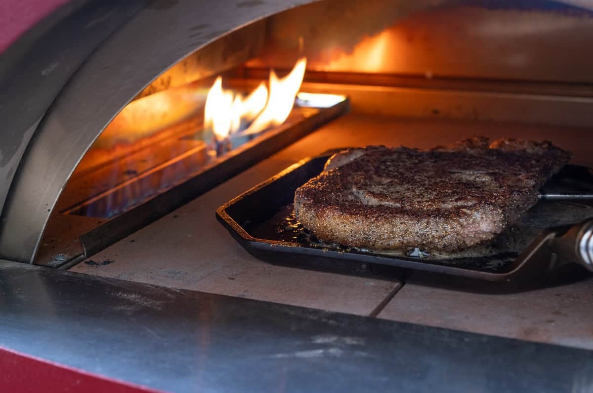 A steak being cooked in an Alfa Forni pizza oven.