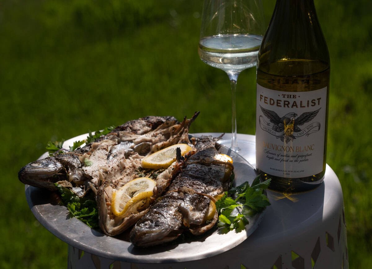 A platter of grilled trout next to a bottle of Sauvignon Blanc wine.
