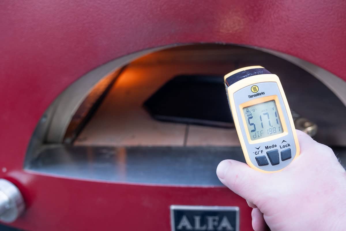 An IR Thermometer taking the temperature of a cast iron pan inside a pizza oven.