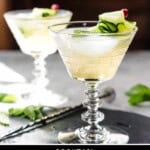 A side shot of two martini glasses with cucumber cocktails on a slate plate.