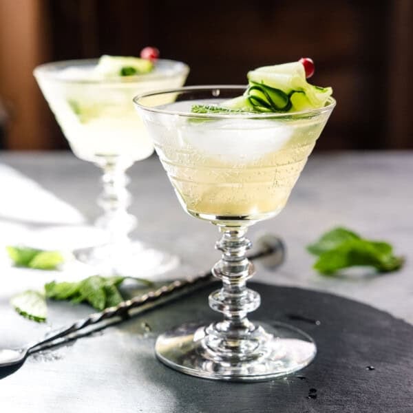 A side shot of a cucumber spritz in a cocktail glass with stem.