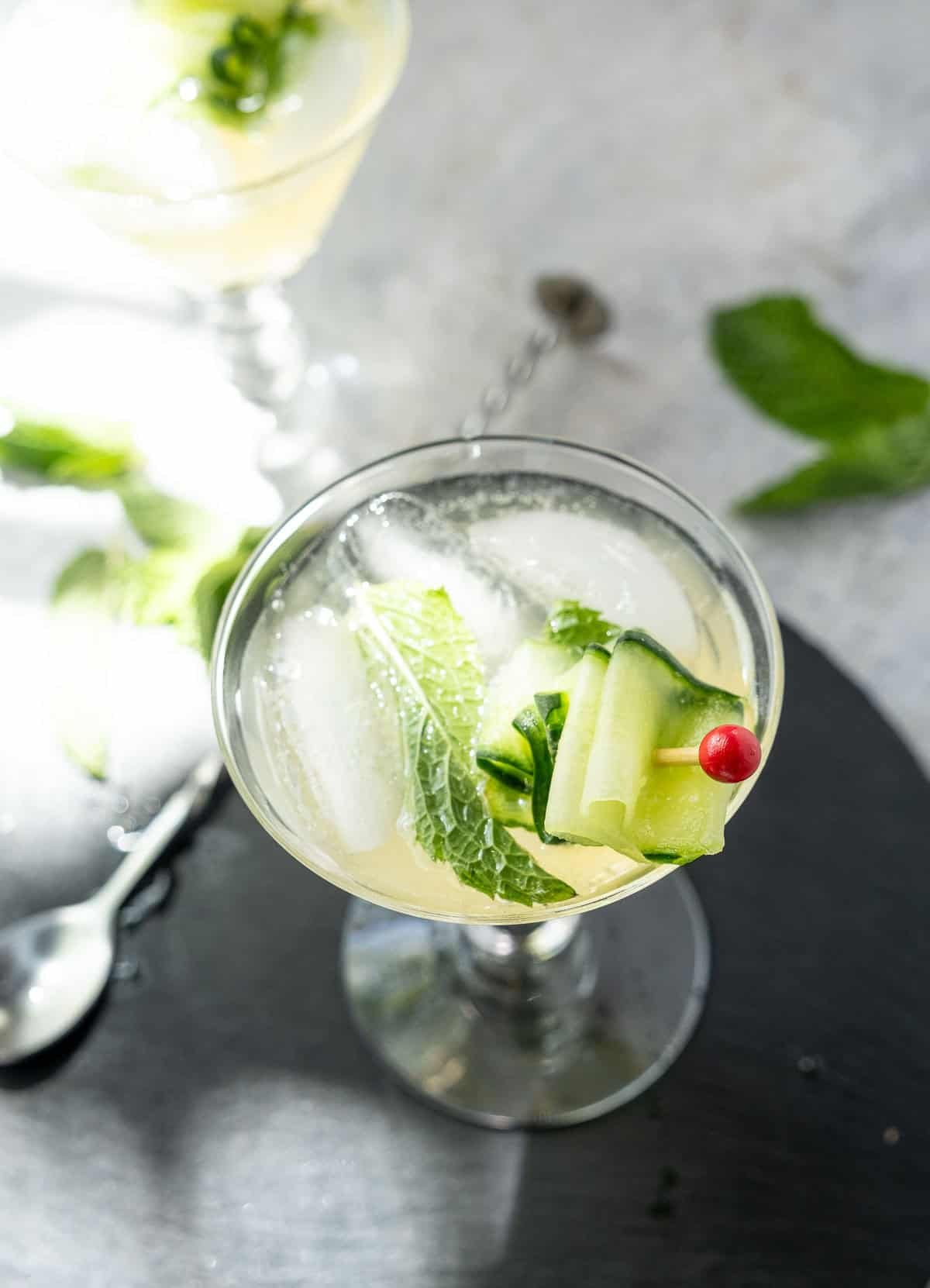 A top down view of a martini glass with a cucumber spritz in it.
