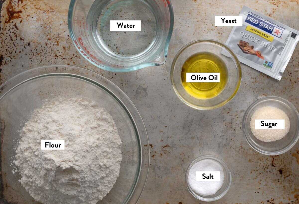 Ingredient photo showing flour, water, salt, sugar, yeast, and salt in glass bowls for a quick pizza dough.