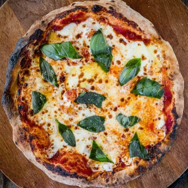 A margherita pizza on a wooden cutting board using a quick one-hour dough.