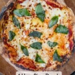 A margherita pizza on a wooden pizza peel.