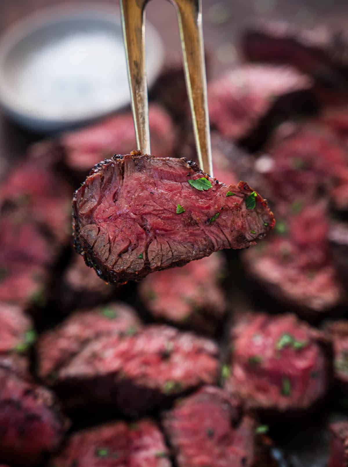 A slice of medium rare hanger steak on a fork.