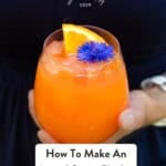 Mary holding an Aperol Spritz slushie with the words how to make a slushie on it.