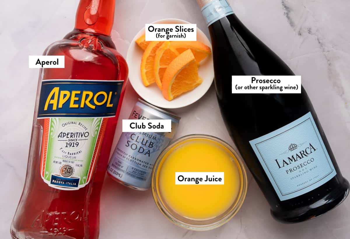 Ingredients for Aperol Spritz Slushie on a white marble table. 