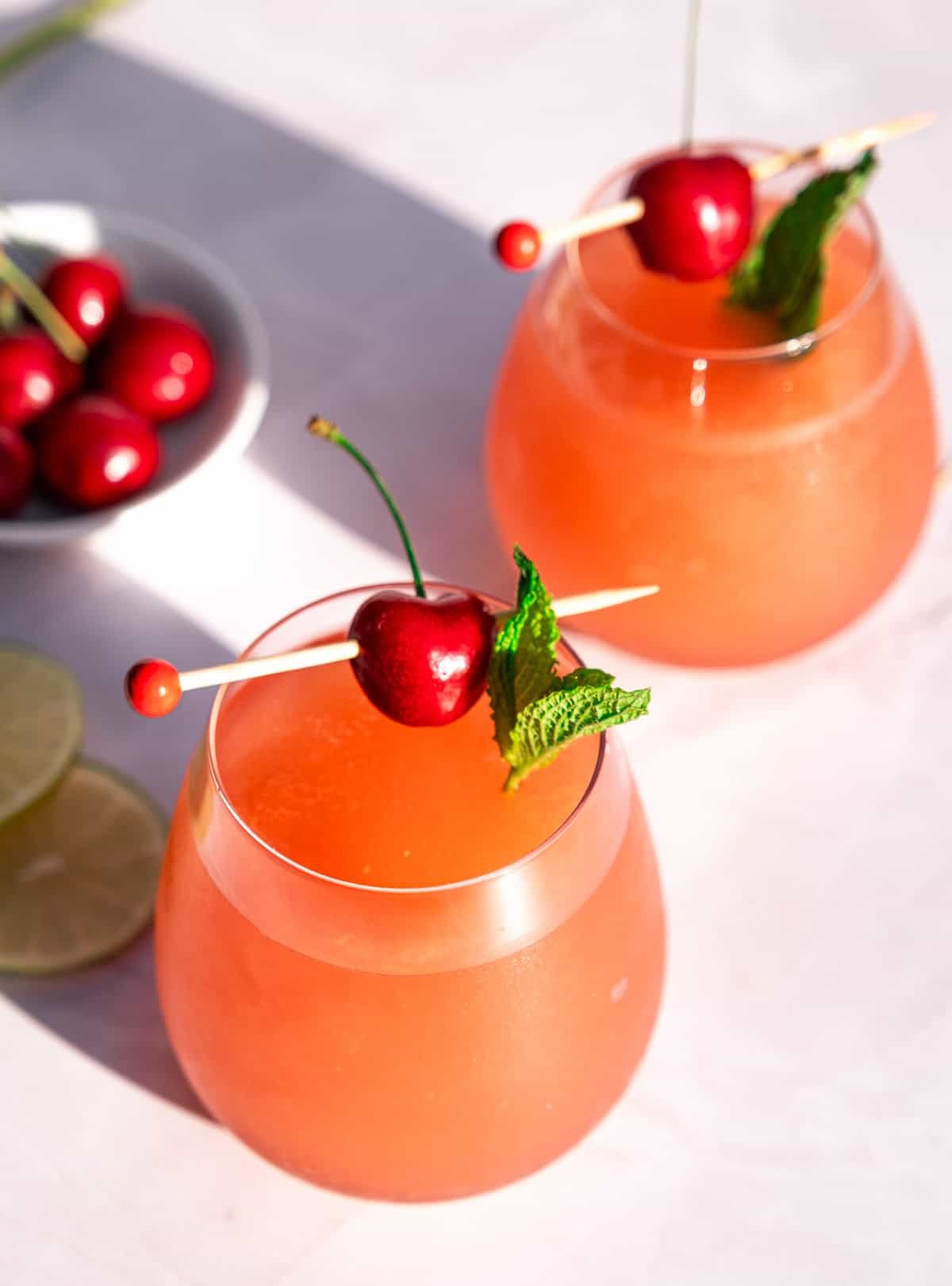Two Rosé Wine slushies in glasses, garnished with mint and cherries. 