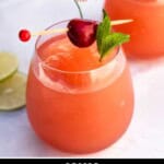 A stemless wine glass filled with a rose wine slushie garnished with cherry and mint.