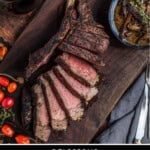 A sliced cowboy ribeye steak on a cutting board.