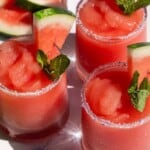 Four cocktail glasses filled with watermelon slushie.