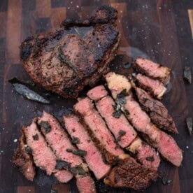 Juicy, perfectly cooked steak with seasoned crust on wooden cutting board.