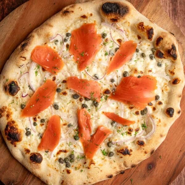 A Smoked Salmon Pizza on a cutting board.