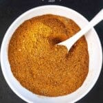 Moroccan spice blend in a large white bowl with a white spoon.