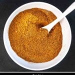 Pinterest pin showing Moroccan spice blend in a large white bowl with a white spoon on a slate plate.
