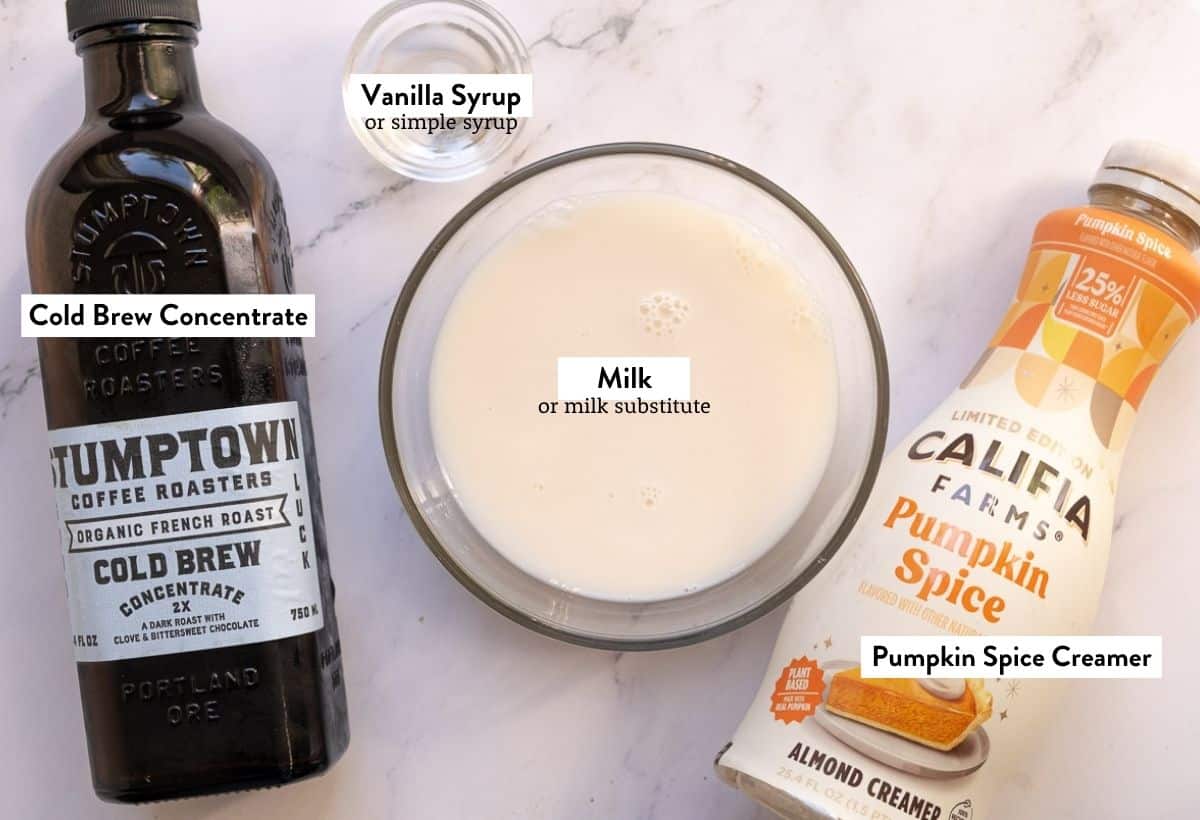 Ingredients for Pumpkin Spice Latte Slushie on a marble table, labeled with the name of ingedient.