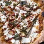 A cut pumpkin fall pizza on parchment paper.