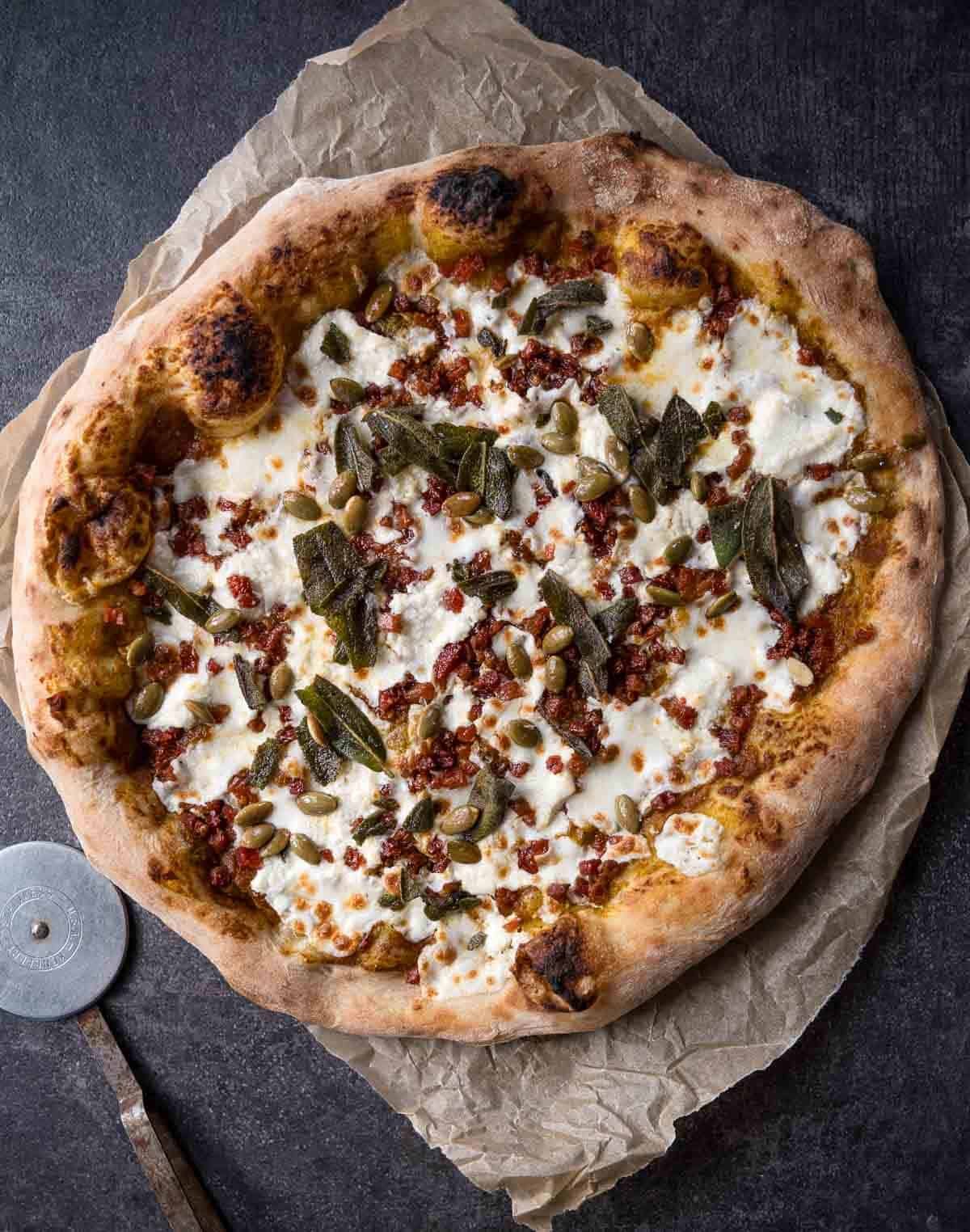 Fall pumpkin and pancetta pizza on a cutting board.
