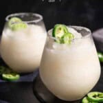 Two glasses of sauvignon blanc slushie topped with candied jalapeno peppers.
