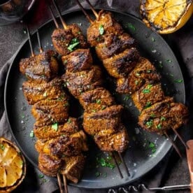 Three Grilled Moroccan Lamb Skewers on a serving platter.