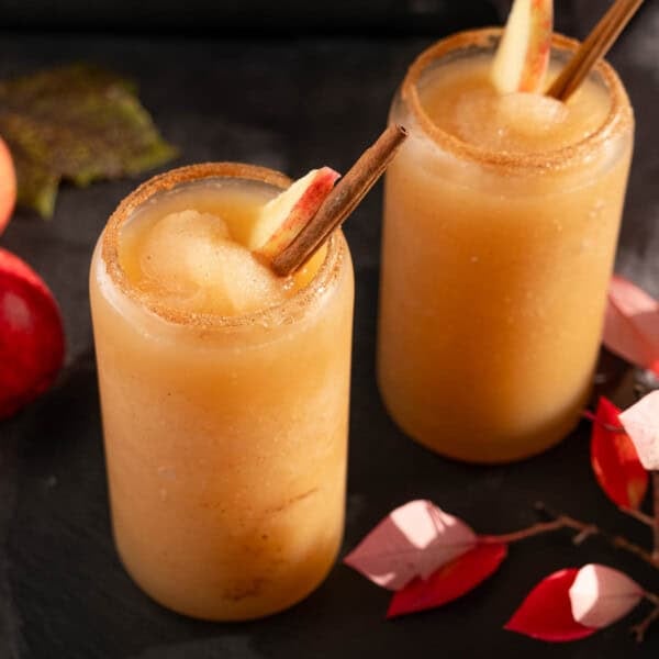 Spiced Apple Cider Slushie on a table garnished with a cinnamon stick and an apple slice.