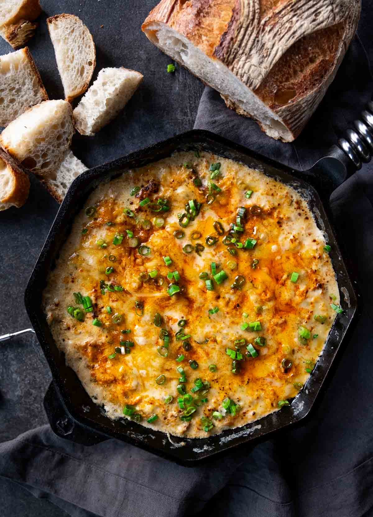 Hot Crab Dip made with Dungeness Crab and Smoked Salmon in a cast iron pan, topped with scallions.