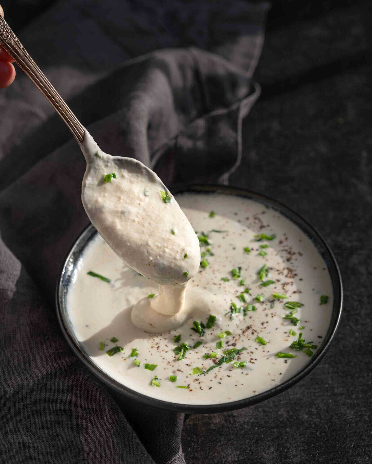 A bowl of creamy horseradish sauce, with a spoon dipping in for a spoonful of the thick and creamy sauce. 
