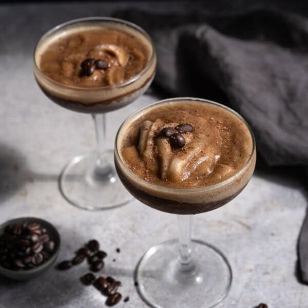 Two Espresso Martini Slushies served in coupe glasses, topped with coffee beans.
