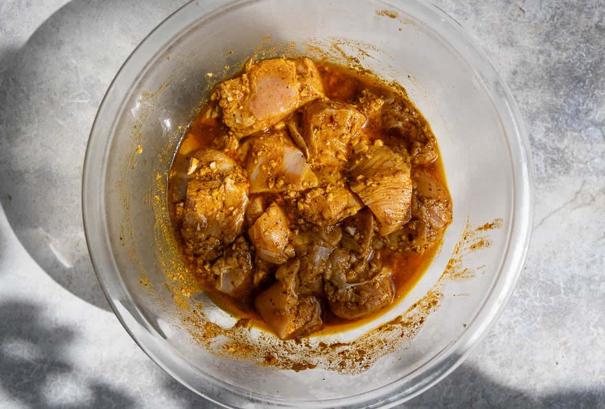 Cubes of chicken sitting in a bowl with a Moroccan marinade.