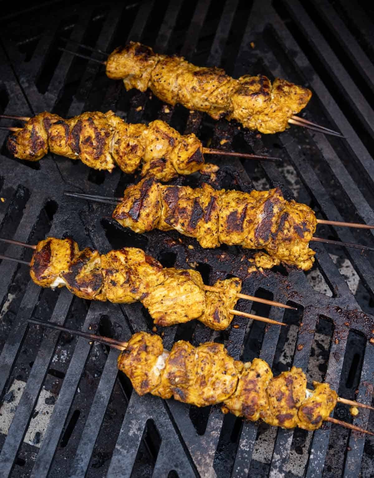Moroccan Chicken skewers cooking on a hot gas grill.